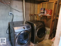 Dedicated laundry area featuring exposed concrete walls and wood framing - 