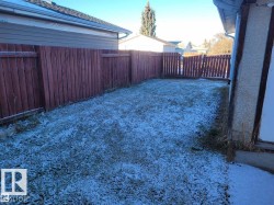 Fenced backyard featuring a wooden privacy fence, a partial gate, and a grass area - 