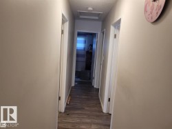 Hallway featuring wood-finish flooring, light neutral wall paint, white trim, and recessed ceiling light - 