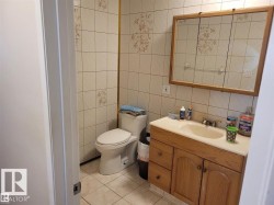 Bathroom featuring patterned wall tiling, a wood-finish vanity with an integrated sink, and a framed mirrored medicine cabinet - 