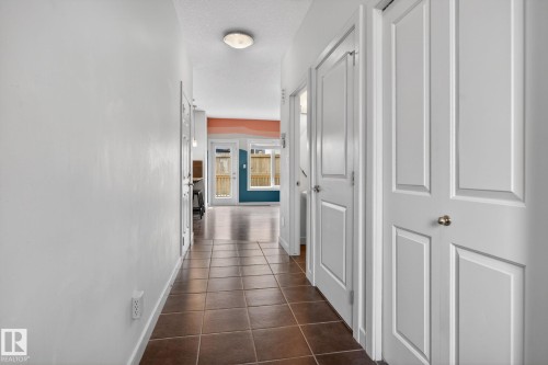 Brown square tile flooring defines a hallway with white paneled doors and walls - 11 450 Mcconachie Way, Edmonton, AB - Indoor Photo Showing Other Room
