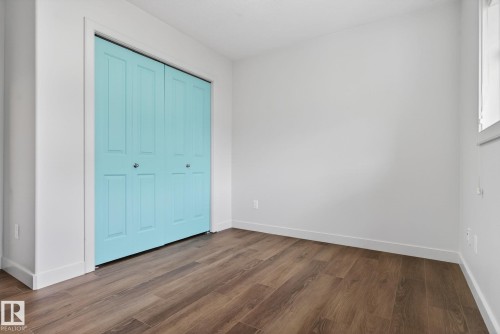 Room featuring wood-finish flooring, crisp white walls, and a window providing natural light - 11 450 Mcconachie Way, Edmonton, AB - Indoor Photo Showing Other Room