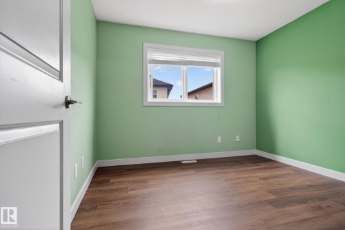 Bright room featuring green painted walls, white trim, wood-finish flooring, and a window with blinds - 11 450 Mcconachie Way, Edmonton, AB - Indoor Photo Showing Other Room