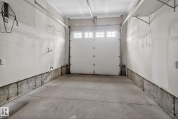 Spacious garage featuring a concrete floor, painted white walls, and a white overhead door with windows - 