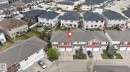 End-unit townhome featuring a red facade and a single-car garage - 11 450 Mcconachie Way, Edmonton, AB  - Outdoor 