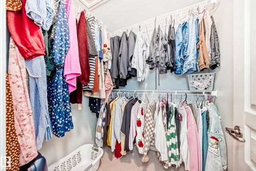 Walk-in closet featuring built-in wire shelving, multiple hanging rods, and light-colored walls - 105 13825 155 Avenue, Edmonton, AB - Indoor With Storage