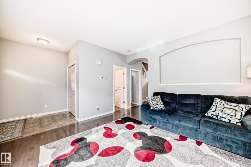 Spacious living area featuring wood-finish flooring, light grey wall paint, and white baseboards - 105 13825 155 Avenue, Edmonton, AB - Indoor Photo Showing Living Room