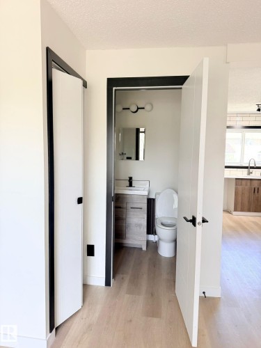 Powder room featuring a modern vanity with a rectangular sink, wall-mounted faucet, and a contemporary spherical vanity light - 11628 151 Avenue Nw, Edmonton, AB 