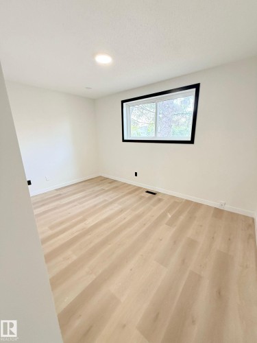 Bright room featuring light wood-finish flooring, recessed ceiling lighting, and a window with black trim - 11628 151 Avenue Nw, Edmonton, AB 