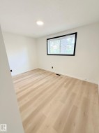 Bright room featuring light wood-finish flooring, recessed ceiling lighting, and a window with black trim - 
