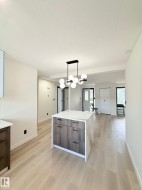 Modern kitchen island featuring a waterfall-edge countertop with veining, wood-finish cabinetry, and matte black hardware - 