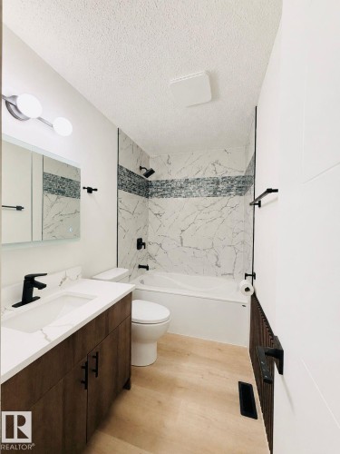 Bathroom featuring a modern vanity with integrated sink, a white countertop, and dark wood-finish cabinetry - 11628 151 Avenue Nw, Edmonton, AB 