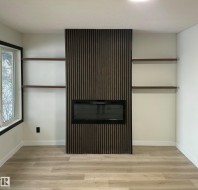 Integrated fireplace with a vertical wood-slat accent wall, flanked by built-in shelving and light wood-finish flooring - 