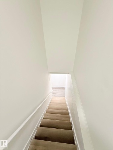 Staircase with wood-finish treads, white painted risers, and a white handrail - 11628 151 Avenue Nw, Edmonton, AB 