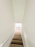 Staircase with wood-finish treads, white painted risers, and a white handrail - 