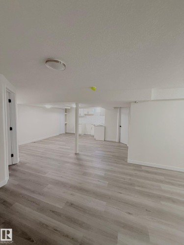 Spacious interior with light wood-finish flooring, white walls, and recessed lighting - 11628 151 Avenue Nw, Edmonton, AB 
