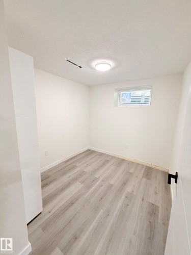 Room featuring light wood-finish flooring, white walls, and a single window with horizontal blinds - 11628 151 Avenue Nw, Edmonton, AB 