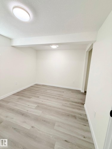Expansive room featuring wood-finish flooring, crisp white walls, and a recessed ceiling light - 11628 151 Avenue Nw, Edmonton, AB 