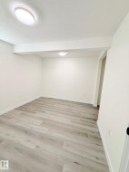 Expansive room featuring wood-finish flooring, crisp white walls, and a recessed ceiling light - 