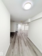 Expansive interior space featuring wood-finish flooring, white walls, and recessed lighting - 