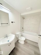Bathroom featuring a white vanity with integrated sink, chrome faucet, and matte black hardware - 