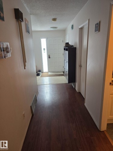 Entryway featuring wood-finish flooring, a paneled front door with a vertical frosted glass insert, and a flush-mount ceiling light - 11927 85 Street Nw, Edmonton, AB - Indoor Photo Showing Other Room