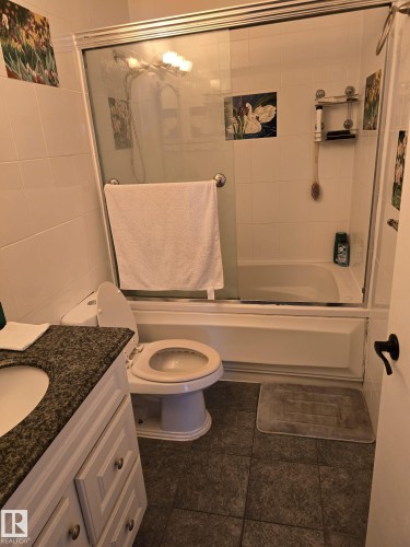 Bathroom featuring a granite-look vanity countertop, light-toned cabinetry, and dark tiled flooring - 11927 85 Street Nw, Edmonton, AB - Indoor Photo Showing Bathroom