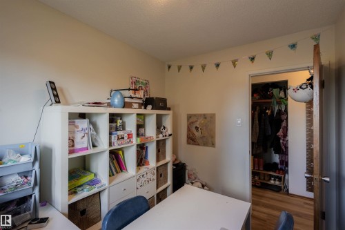 Bedroom featuring light neutral wall tones, a ceiling light fixture, a closet with wood-finish flooring, and a solid wood door - 5931 138 Avenue, Edmonton, AB - Indoor