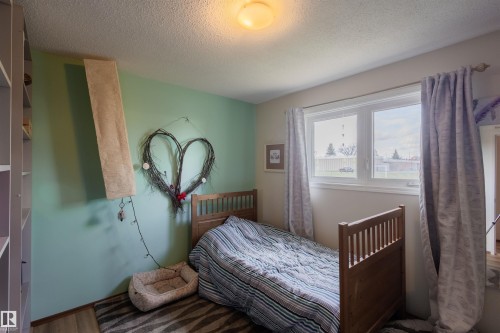 Bright interior space featuring a double-pane window, wood-finish flooring, and a built-in shelving unit - 5931 138 Avenue, Edmonton, AB - Indoor Photo Showing Bedroom