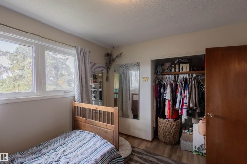 Recessed closet with clothes rod and shelving, accompanied by a wood-finish door - 5931 138 Avenue, Edmonton, AB - Indoor Photo Showing Bedroom
