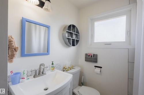 Bathroom featuring a vanity with an integrated sink, a tiled backsplash, and a window for natural light - 5931 138 Avenue, Edmonton, AB - Indoor Photo Showing Bathroom