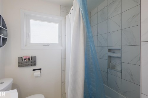 Shower enclosure featuring white tiled walls with subtle veining and an integrated recessed niche - 5931 138 Avenue, Edmonton, AB - Indoor Photo Showing Bathroom