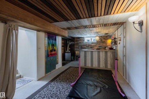 Finished basement featuring a wood-panel accent wall and ceiling, built-in bar with wood-finish paneling, window, and carpeted flooring - 5931 138 Avenue, Edmonton, AB - Indoor