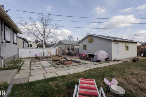 Expansive backyard featuring a concrete patio with a central fire pit area - 5931 138 Avenue, Edmonton, AB - Outdoor