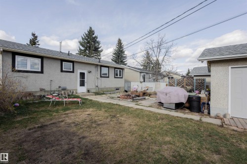 Expansive rear yard featuring a detached garage, concrete patio, and mature trees - 5931 138 Avenue, Edmonton, AB - Outdoor