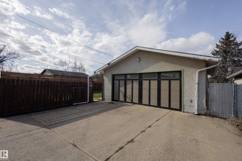 Detached garage with a stucco exterior, featuring a multi-panel door with upper window inserts - 5931 138 Avenue, Edmonton, AB - Outdoor With Exterior