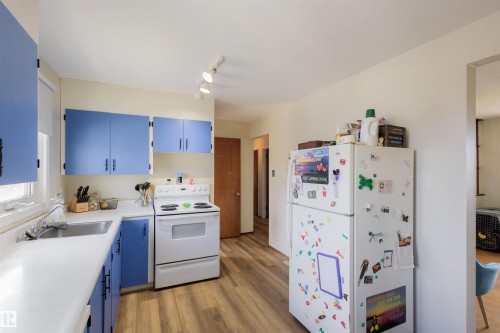 Kitchen area with blue cabinetry, white countertops, white electric range, and wood-finish flooring - 5931 138 Avenue, Edmonton, AB - Indoor Photo Showing Kitchen