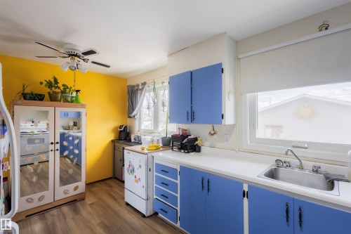 Kitchen featuring wood-finish flooring, white countertops, and blue cabinetry with black hardware - 5931 138 Avenue, Edmonton, AB - Indoor Photo Showing Kitchen