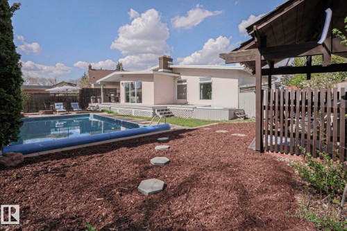 Expansive backyard featuring an in-ground swimming pool, a multi-level deck, and a private hot tub area with a wooden privacy fence and pergola - 1214 85 Street Nw, Edmonton, AB - Outdoor With In Ground Pool