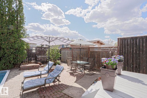 Outdoor living space featuring a white painted deck, brick paver patio, and a gravel area surrounding a pool - 1214 85 Street Nw, Edmonton, AB - Outdoor With Deck Patio Veranda