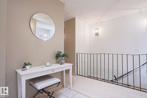 Wrought iron railing defining the stairwell, complemented by vertical shiplap wall paneling and wall sconce lighting - 1214 85 Street Nw, Edmonton, AB - Indoor