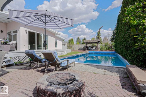 Expansive backyard featuring a rectangular swimming pool, brick paver patio, and a built-in fire pit - 1214 85 Street Nw, Edmonton, AB - Outdoor With In Ground Pool With Deck Patio Veranda