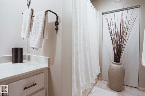 White cabinetry with decorative hardware, a light-colored countertop, and a dark, ornate towel bar - 1214 85 Street Nw, Edmonton, AB - Indoor Photo Showing Bathroom