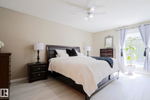 Bedroom featuring light wood-finish flooring, a large window with drapes, a ceiling fan with integrated lighting, and neutral wall tones - 1214 85 Street Nw, Edmonton, AB - Indoor Photo Showing Bedroom