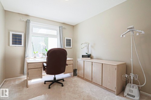 Carpeted room featuring a window with drapes, a built-in desk, and built-in cabinetry - 1214 85 Street Nw, Edmonton, AB - Indoor Photo Showing Office