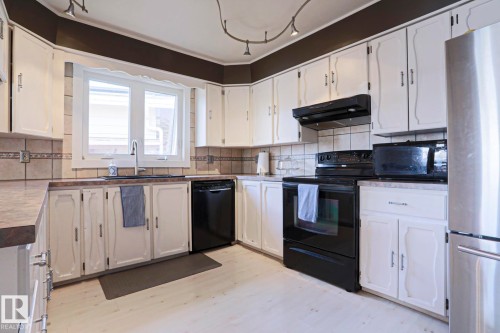 Kitchen featuring white cabinetry with dark hardware, dark countertops, and a tiled backsplash - 1214 85 Street Nw, Edmonton, AB - Indoor Photo Showing Kitchen