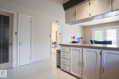 Kitchen cabinetry featuring decorative paneling, an extended countertop, and upper storage with integrated lighting - 1214 85 Street Nw, Edmonton, AB - Indoor