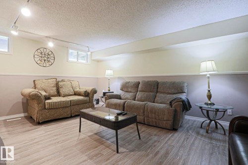 Finished living space featuring wood-finish flooring, track lighting, and a chair rail with two-tone walls - 1214 85 Street Nw, Edmonton, AB - Indoor Photo Showing Other Room