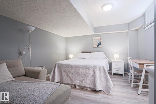 Spacious room featuring wood-finish flooring, light gray walls, and a textured ceiling - 1214 85 Street Nw, Edmonton, AB - Indoor Photo Showing Bedroom