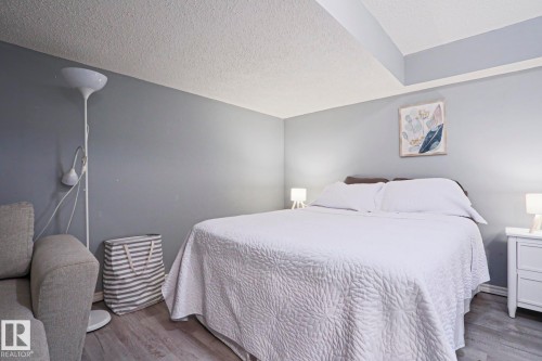 Bedroom featuring light gray walls, wood-finish flooring, and a white nightstand - 1214 85 Street Nw, Edmonton, AB - Indoor Photo Showing Bedroom